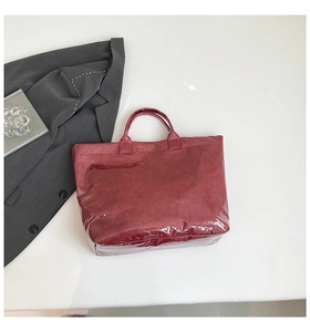 Macro shot of glossy burgundy waterproof tote bag on white background with props