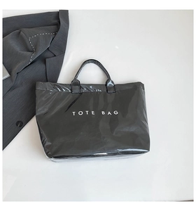 Detail of waterproof black Tyvek tote bag with white text over a grey office blazer