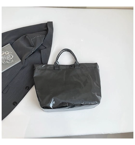 Glossy black waterproof tote bag styled with a gray suit and magazine for a fashion look