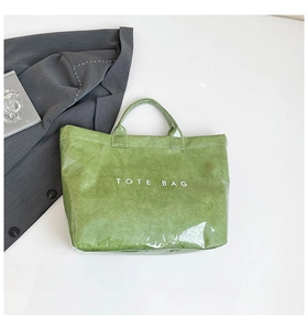 Detail of green DuPont paper tote bag showing glossy texture and TOTE BAG lettering