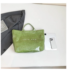 Detail of waterproof bright green tote bag with crinkle texture and white lettering