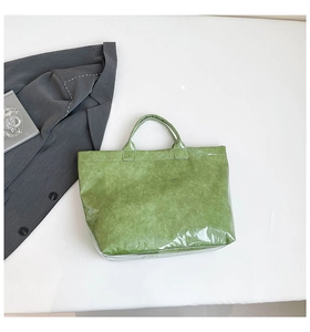 Flat lay of a green Dupont paper tote bag with transparent PVC overlay on white background