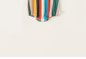 Detail of colorful striped baby romper showing convenient bottom snap button closure
