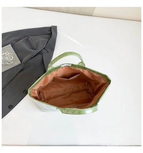 Detail of light green patent leather tote bag showing brown lining and inner pockets