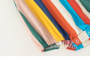 Detail of colorful rainbow striped baby romper with metallic snap buttons and elastic cuffs