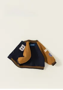 Detail of the embroidered letter B and striped ribbed cuffs on children's baseball jacket