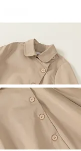 Detailed close-up of beige twill cotton kids trench coat with buttons and collar