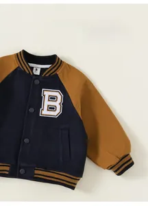 Detailed view of kids varsity jacket with letter B embroidery and navy brown contrast sleeves