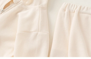 Détail d'un survêtement côtelé crème pour enfant avec taille élastique et fermeture