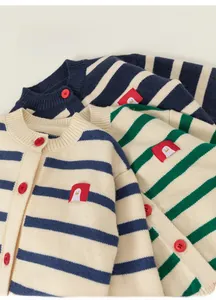 Detail of children striped knit cardigan with red penguin patch and vibrant red buttons
