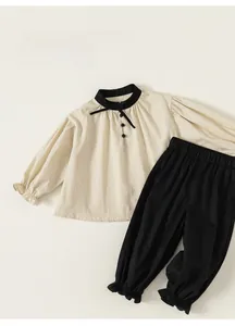 Detail of baby girl doll blouse with bow collar and black jogger pants outfit