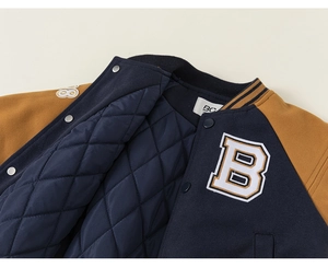Detail of kids baseball jacket showing quilted diamond lining and navy embroidery patch