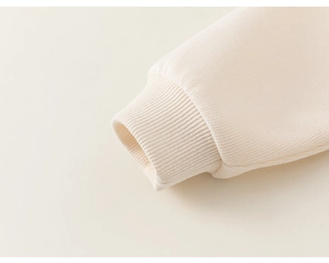 Gros plan des poignets côtelés d'un sweat à capuche pour enfant de couleur crème