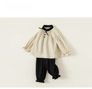 Detail of girls beige blouse with black bow and matching gathered pants set