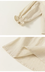 Detail of cream blouse featuring textured vertical stripes and ruffled elastic sleeve cuffs