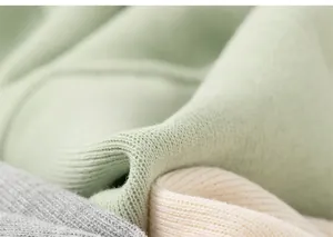 Detailed macro view of soft ribbed cotton knit fabric in pastel green and grey tones