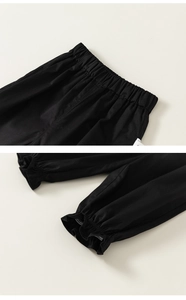 Detail of elastic high-waist band and ruffle hem cuffs on black cotton girl trousers