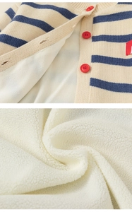 Detail of warm white sherpa lining and navy striped knit cardigan with red buttons