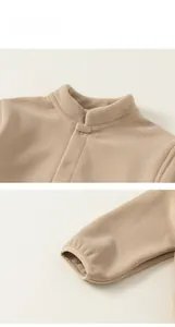 Détail d'une veste en polaire beige avec col montant, boutons-pression et poignets élastiques