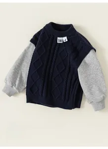 Close-up of boys' knitted patchwork sweatshirt in navy blue and grey with dinosaur tag
