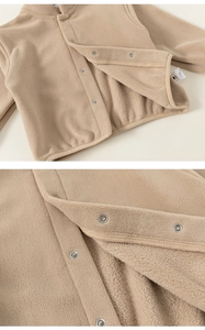 Détail d'une veste en polaire beige pour enfant avec boutons-pression et texture douce