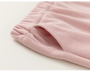 Detailed view of pink cotton knit trousers featuring elastic waist and side pocket