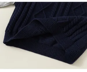Detailed knit texture of boys' navy blue sweater with classic cable and diamond patterns