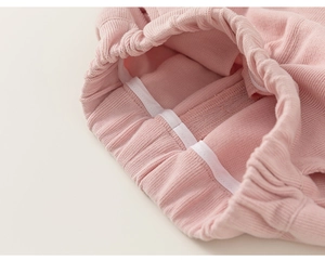 Detail of pink knitted cotton pants featuring a high elastic ribbed waistband for kids