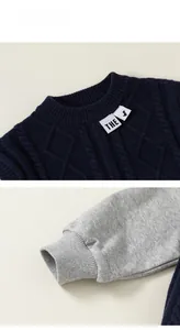 Detail view of boys' knitted sweater featuring navy diamond weave and grey ribbed cuffs