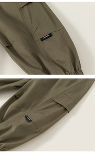 Detailed close-up of olive green cargo pants with flap pockets and elastic cuffs