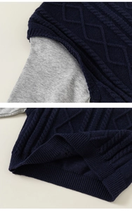 Detail of navy blue cable knit vest with grey sleeves showing ribbed hem texture