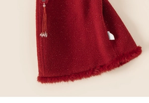 Detail of red traditional dress with faux fur trim, golden sequins and tassel pendant