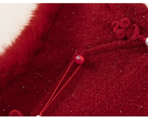 Detailed close-up of red tweed fabric with pearls and rhinestones on a princess dress