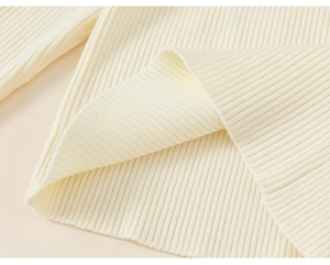 Close-up of cream-colored knit dress showing soft ribbed texture and premium fabric details