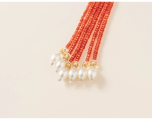 Detail of orange seed bead tassels featuring white faux pearls and yellow spacer beads