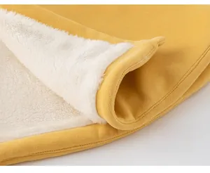 Détail d'une cape jaune pour enfant avec doublure épaisse en polaire blanche pour l'hiver