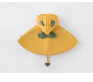 Vue détaillée du poncho jaune pour bébé avec cornes de monstre et ailes décoratives
