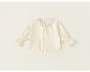 Detail of baby beige cotton blouse with ruffle collar and hollow embroidery textures