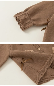 Detail of brown knit cardigan featuring ribbon bow accents and round wooden buttons