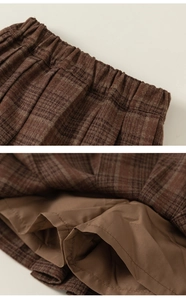Detail view of brown plaid pleated skirt featuring elastic waistband and inner lining