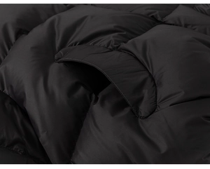Detailed macro view of black puffer jacket showing pocket flap and quilted windproof fabric