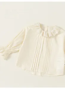 Detailed close-up of girls' creamy white shirt with eyelet lace collar and pleated front