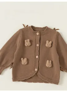Close-up of brown knit cardigan featuring plush bunny patches and satin bows detail
