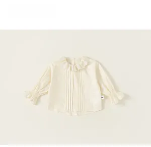 Detail of girls' cream blouse featuring embroidered lace collar and pleated chest design