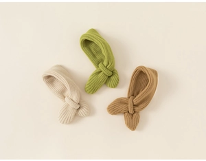 Detail of three ribbed knit neck warmers in beige, green, and khaki on a cream background