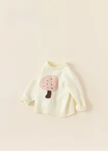 Detailed flat lay of cream knit sweater for kids featuring a cute pink mushroom pattern