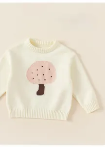 Close-up of cream knit sweater showing pink mushroom jacquard and soft cotton texture
