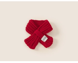 Dettaglio ravvicinato di una mini sciarpa in maglia rossa con etichetta SWIM SLOWLY