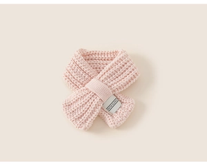 Dettaglio mini sciarpa in maglia rosa con etichetta tessuta bianca decorativa