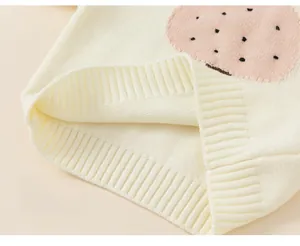 Close-up of the soft knit texture and cute round patch on this cream toddler sweater